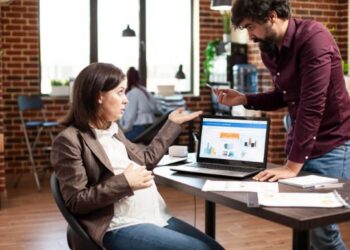 Marketing team analyzing SEO and paid search performance on a laptop dashboard, discussing cross-channel strategy and conversion optimization in a modern office.