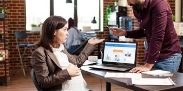 Marketing team analyzing SEO and paid search performance on a laptop dashboard, discussing cross-channel strategy and conversion optimization in a modern office.