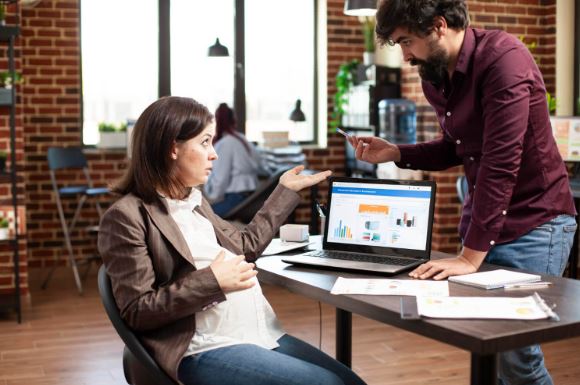 Marketing team analyzing SEO and paid search performance on a laptop dashboard, discussing cross-channel strategy and conversion optimization in a modern office.